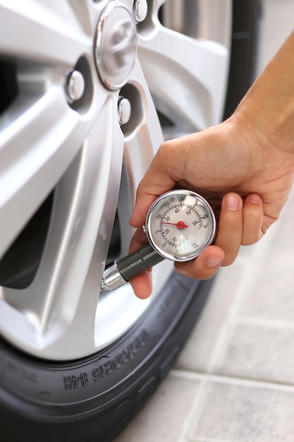 Concepto de seguridad del vehículo Primer plano de la mano que sostiene el manómetro para la medición de la presión de los neumáticos del coche