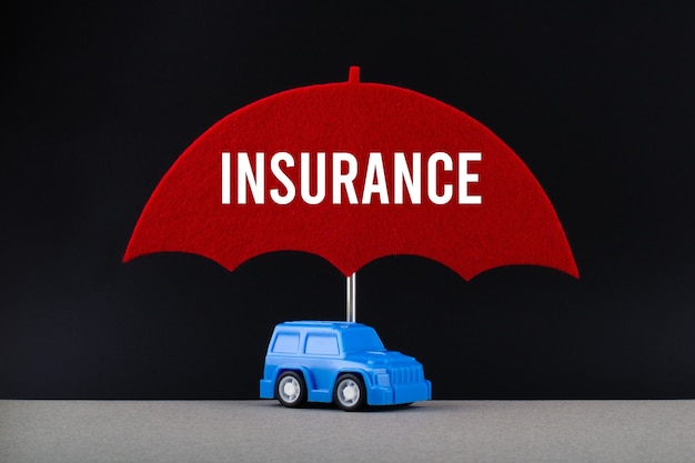 Concepto de seguro de automóvil. Coche azul bajo la sombrilla roja con texto Seguro.