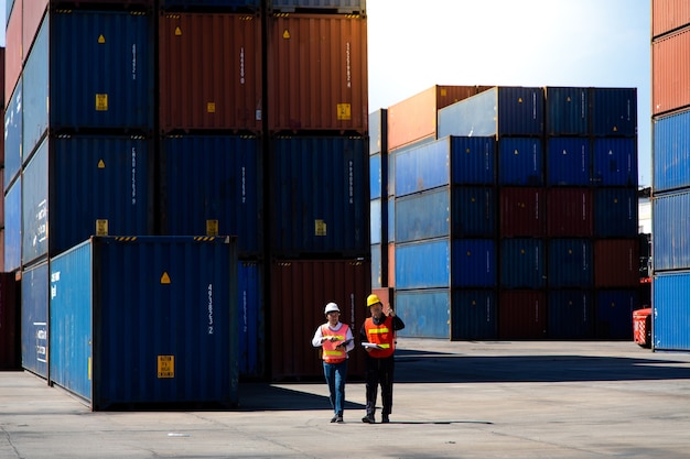 Concepto de seguro marítimo y de transporte. Hombre del puerto dos que trabaja en el patio de contenedores. El capataz controla la caja de contenedores de carga en el puerto de envío. Concepto de importación y exportación logística empresarial.