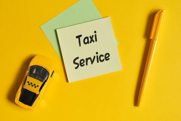 Concepto de servicio de taxi como una inscripción en una pegatina junto a un coche de juguete en una pared amarilla