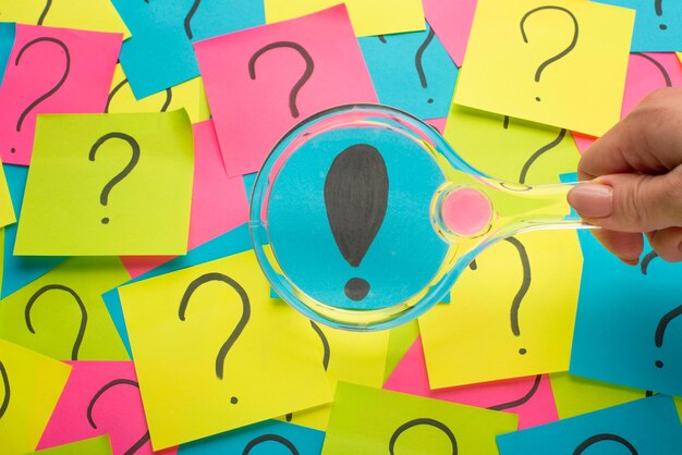 Concepto con un signo de exclamación en una nota adhesiva y una lupa