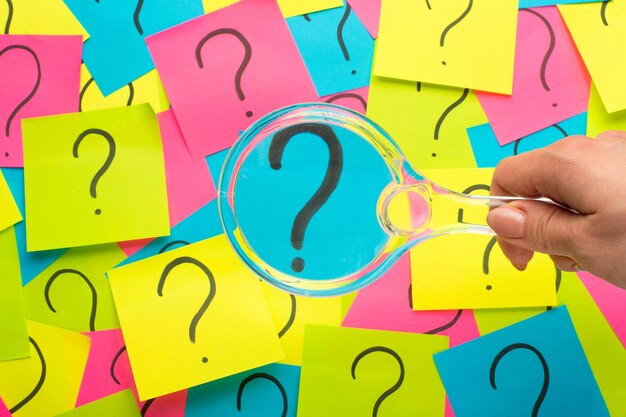 Concepto con signo de interrogación en nota adhesiva y lupa