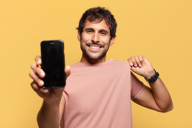 Concepto de smartphone expresión orgullosa joven guapo indio