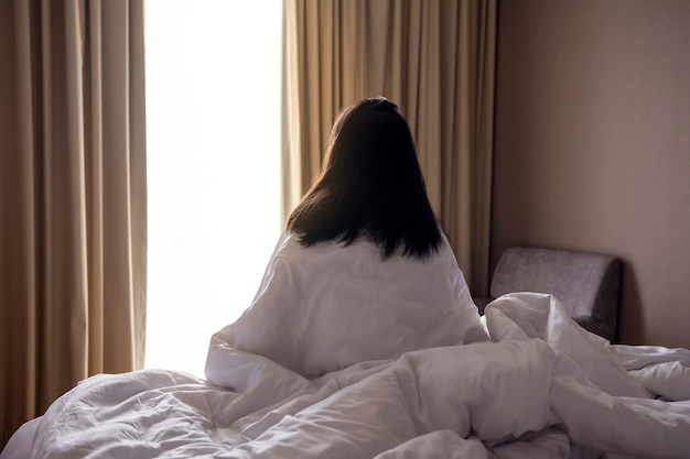 Concepto de soledad y tristeza. Mujer sentada en la cama y mirando afuera