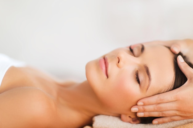 Concepto de spa, resort, belleza y salud - hermosa mujer en el salón de spa recibiendo tratamiento facial