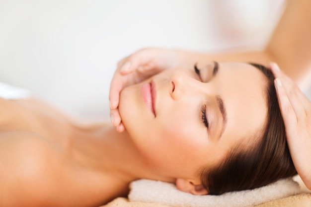 Concepto de spa, resort, belleza y salud - hermosa mujer en el salón de spa recibiendo tratamiento facial