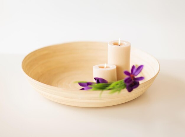 concepto de spa, salud y belleza - velas y flores de iris en cuenco de madera