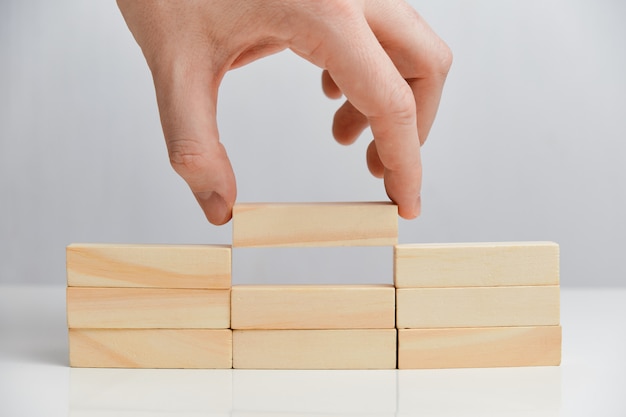 El concepto de tareas básicas. La mano sostiene los bloques de madera en un espacio en blanco.