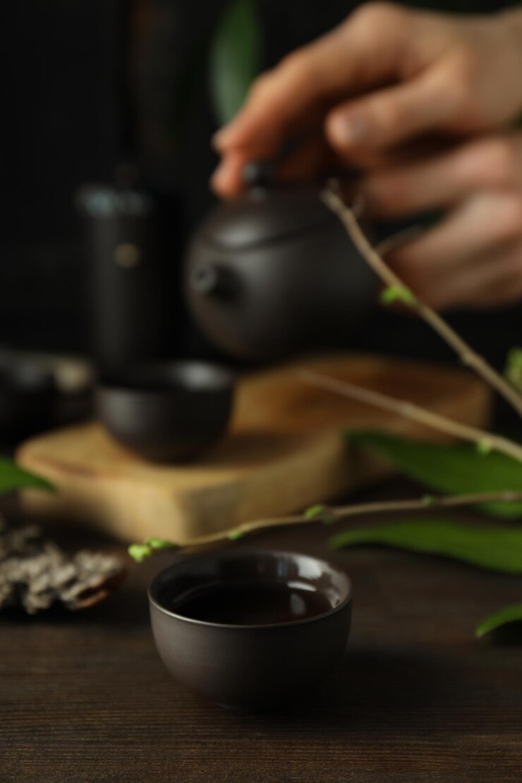 El concepto de té asiático sobre un fondo oscuro con plantas.