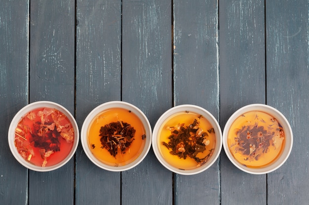 Concepto de té Diferentes tipos de té seco en cuencos de cerámica y tazas de té aromático.