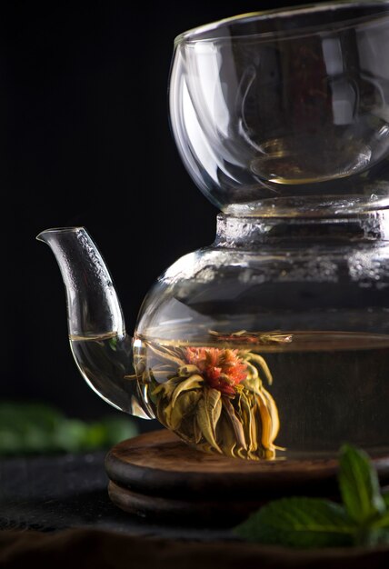 Concepto de té, tetera con té rodeado sobre fondo de madera, ceremonia del té, té verde en una taza transparente