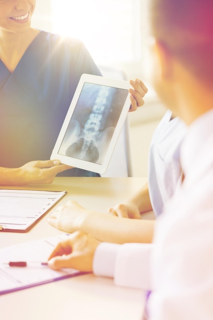 concepto de tecnología, cirugía, personas y medicina - cierre de doctores felices discutiendo rayos X en una computadora de tablet pc en el hospital,