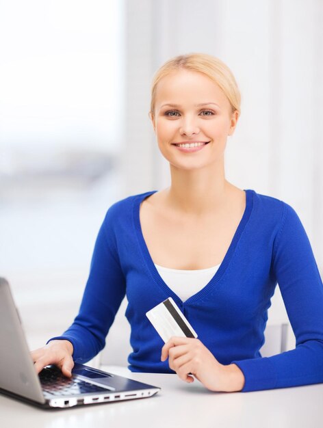 Concepto de tecnología y compras en línea - mujer joven sonriente con computadora portátil y tarjeta de crédito