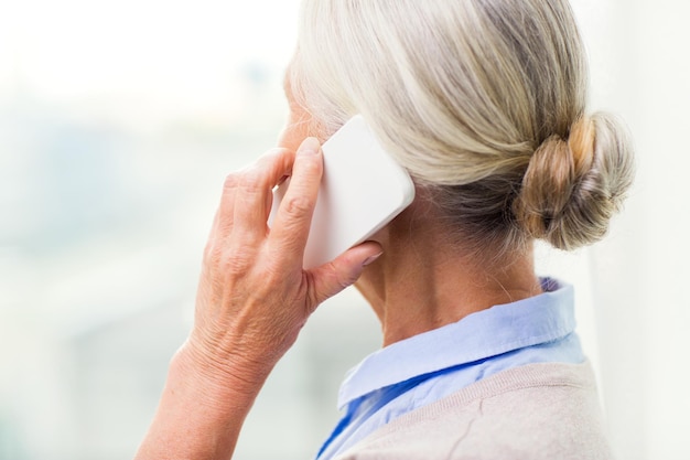 concepto de tecnología, comunicación, edad y personas - cierre de una anciana con teléfono inteligente llamando a casa