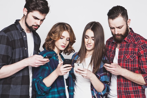 Foto concepto de tecnología e internet: grupo de jóvenes mirando sus teléfonos inteligentes