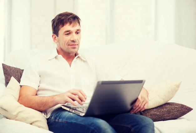 concepto de tecnología y estilo de vida - hombre que trabaja con la computadora portátil en casa