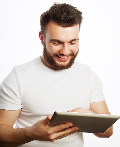 Concepto de tecnología y estilo de vida joven vestido con camiseta blanca usando una tableta aislada sobre un fondo blanco