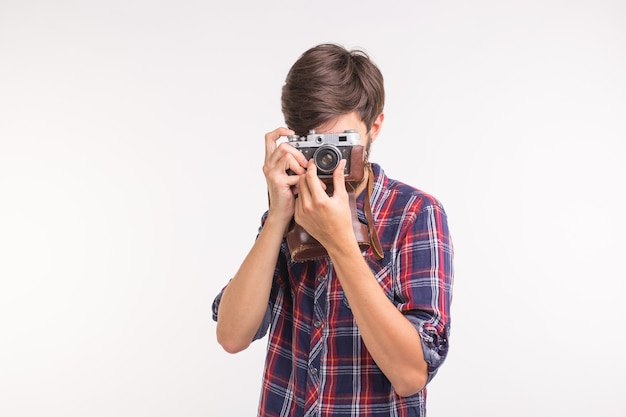 Concepto de tecnología, fotografía y personas - hombre guapo en camisa a cuadros tomando una foto con cámara retro.