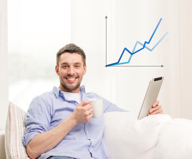 Foto concepto de tecnología, hogar y estilo de vida - hombre sonriente que trabaja con una tableta y una taza de café en casa