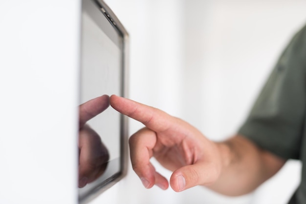 concepto de tecnología y hogar inteligente primer plano de las manos masculinas que señalan con el dedo a la computadora tablet pc integrada en la pared interior de la casa