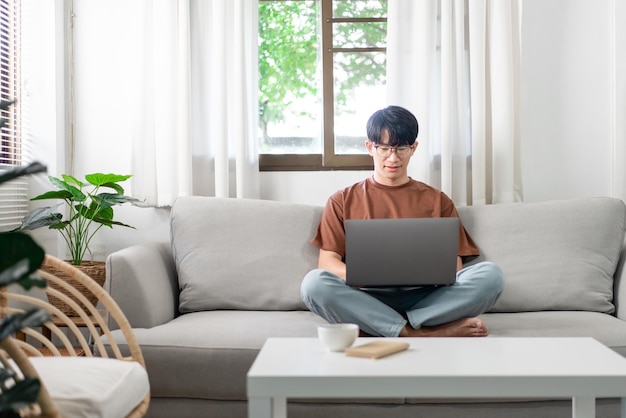 Concepto de tecnología El hombre que lleva ropa informal sentado en el sofá