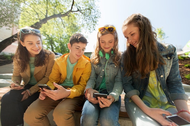 concepto de tecnología, internet y personas - amigos adolescentes felices con smartphones al aire libre