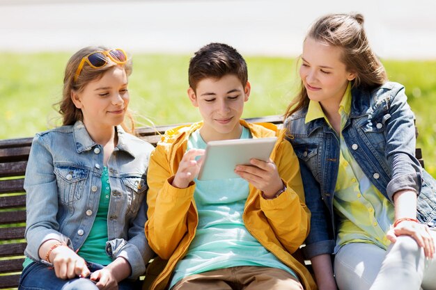 concepto de tecnología, internet y personas - grupo de amigos adolescentes felices o estudiantes con computadora de tablet pc al aire libre