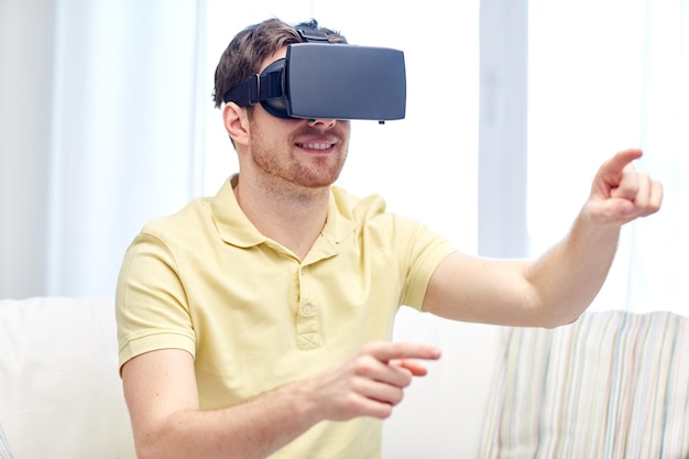 concepto de tecnología, juegos, entretenimiento y personas - joven feliz con auriculares de realidad virtual o gafas 3d jugando videojuegos