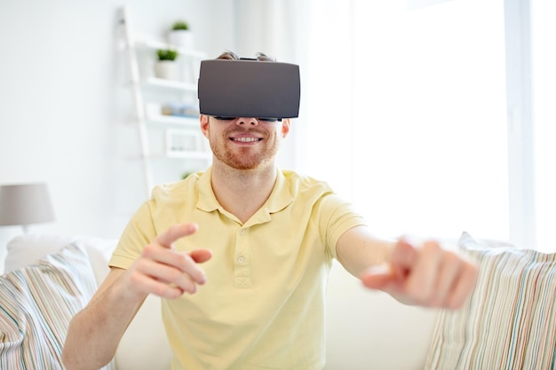 concepto de tecnología, juegos, entretenimiento y personas - joven feliz con auriculares de realidad virtual o gafas 3d jugando videojuegos