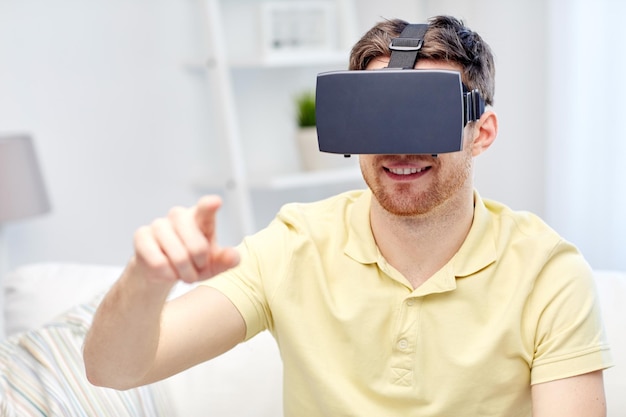 concepto de tecnología, juegos, entretenimiento y personas - joven feliz con auriculares de realidad virtual o gafas 3d jugando videojuegos