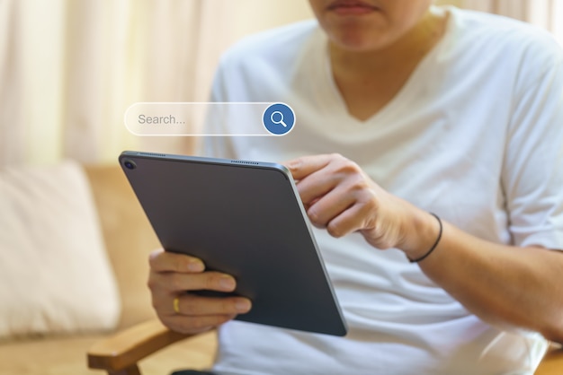 Concepto de tecnología. Mano de hombre sosteniendo y usando tableta de computadora con icono de cuadro de barra de búsqueda.