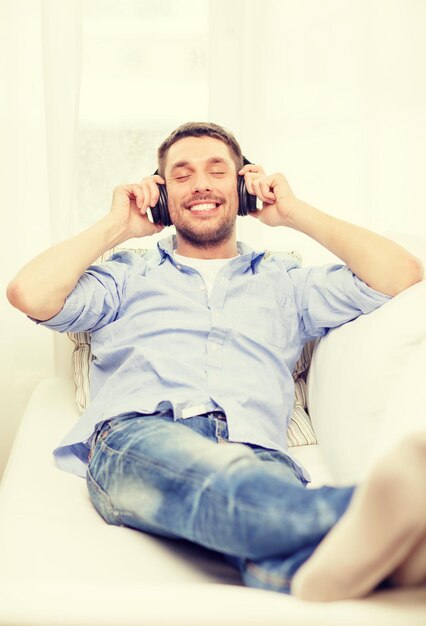 concepto de tecnología, música y felicidad - joven sonriente con auriculares en casa