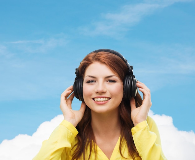 concepto de tecnología, música y felicidad - niña sonriente con auriculares en casa