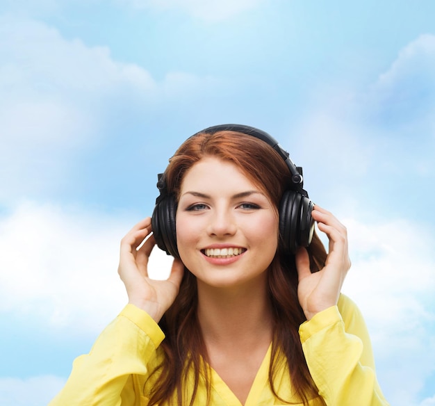 concepto de tecnología, música y felicidad - niña sonriente con auriculares en casa