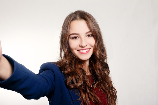 Foto concepto de tecnología, negocios, belleza y estilo de vida - retrato de mujer joven belleza haciendo selfie sobre fondo gris.