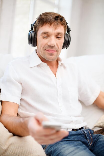 concepto de tecnología, ocio y estilo de vida - hombre feliz con auriculares escuchando música en casa