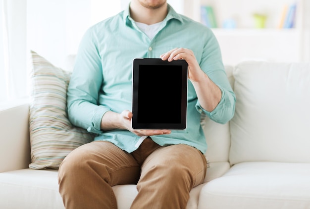 concepto de tecnología, ocio, estilo de vida y publicidad: cierre de un hombre que trabaja con una computadora de tablet pc sentado en un sofá en casa