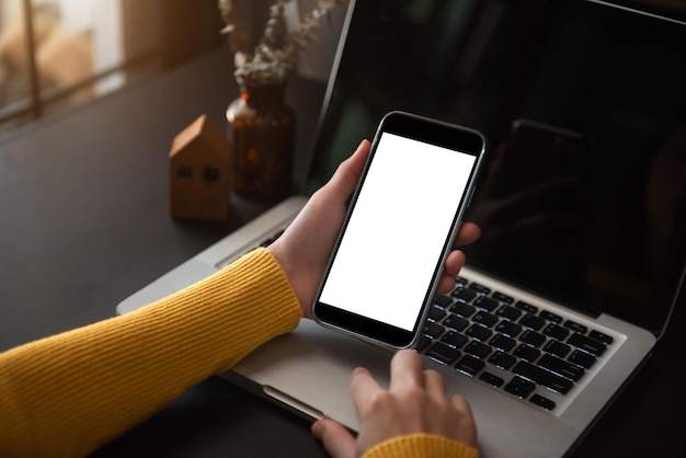 Concepto de tecnología y oficina de negocios Mano que sostiene el teléfono móvil con pantalla en blanco en la oficina