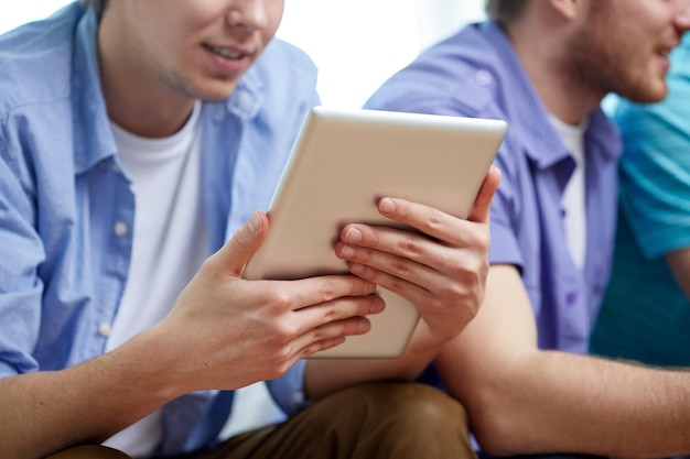 concepto de tecnología y personas - cerca de amigos felices con computadoras tablet pc en casa