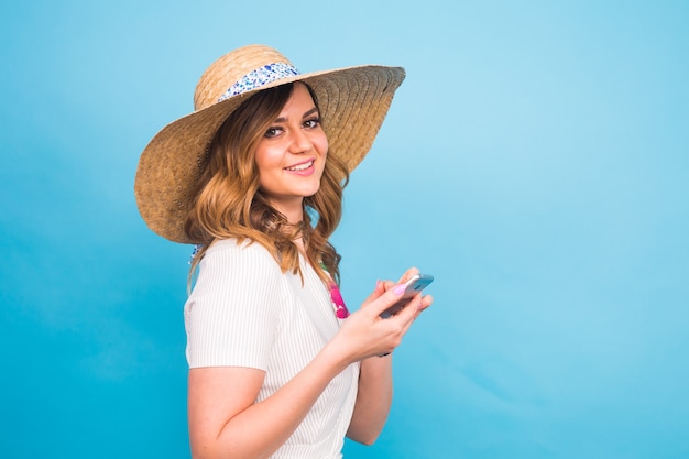 Concepto de tecnología, personas y dispositivos modernos - mujer sonriente escribiendo en el teléfono, mensaje de texto vista lateral sobre fondo azul con espacio de copia.