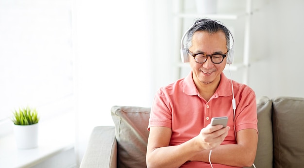 concepto de tecnología, personas y estilo de vida - hombre feliz con smartphone y auriculares escuchando música en casa