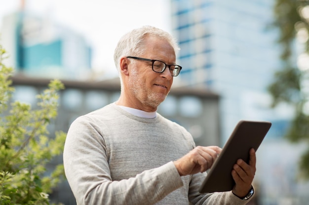 concepto de tecnología, personas y estilo de vida - hombre mayor con tablet pc en la calle de la ciudad