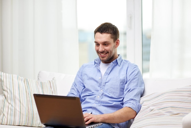 concepto de tecnología, personas y estilo de vida - hombre sonriente trabajando con una laptop en casa