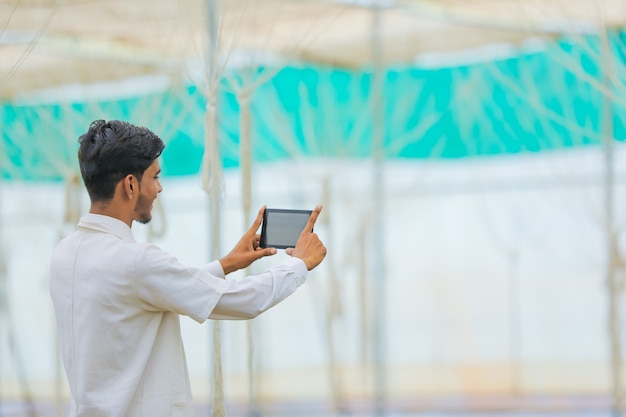 Concepto de tecnología y personas, joven agrónomo indio con tableta en invernadero