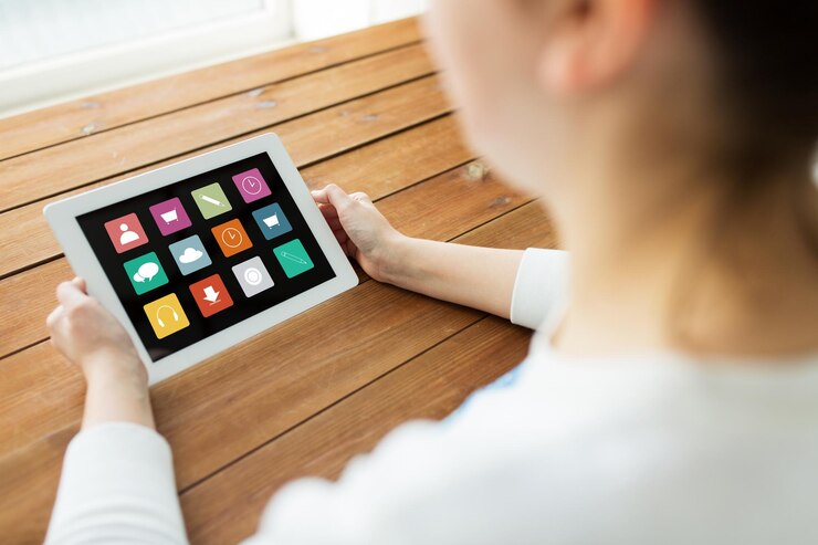 Foto concepto de tecnología, personas y medios: cierre de una mujer con iconos de menú en la pantalla de la computadora de tablet pc en una mesa de madera