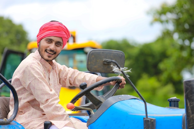 Concepto de tecnología y personas, retrato de joven agricultor indio con tractor