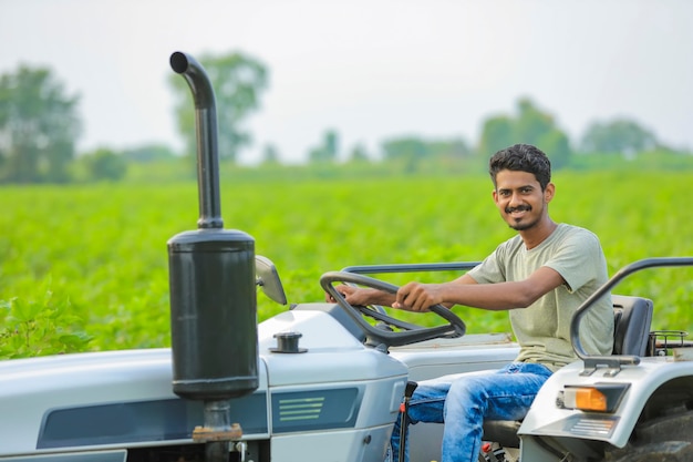 Concepto de tecnología y personas, retrato de joven agricultor indio con tractor