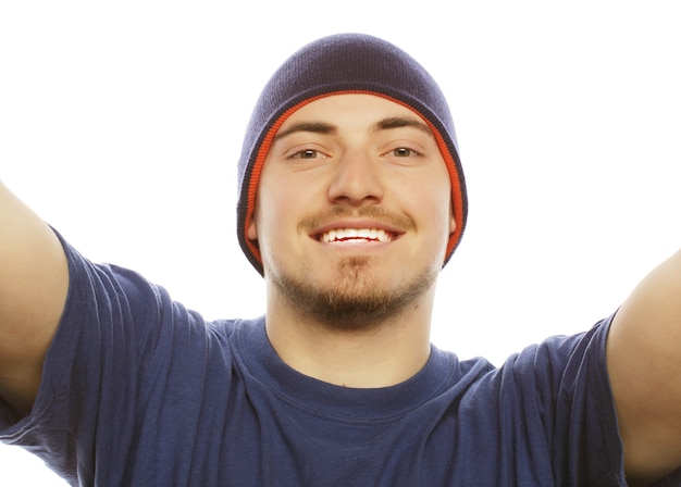 Concepto de tecnología y personas: selfie feliz. Apuesto joven sosteniendo la cámara y haciendo selfie y sonriendo.