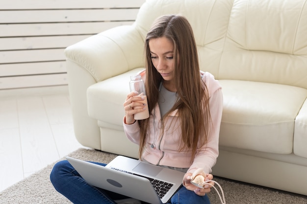 Concepto de tecnologías, autónomos y personas - mujer joven que trabaja en casa, ella está bebiendo agua