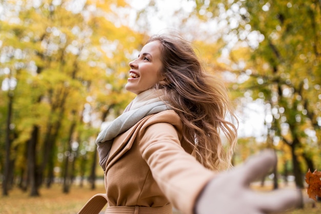 concepto de temporada y gente - hermosa mujer joven feliz caminando en el parque de otoño